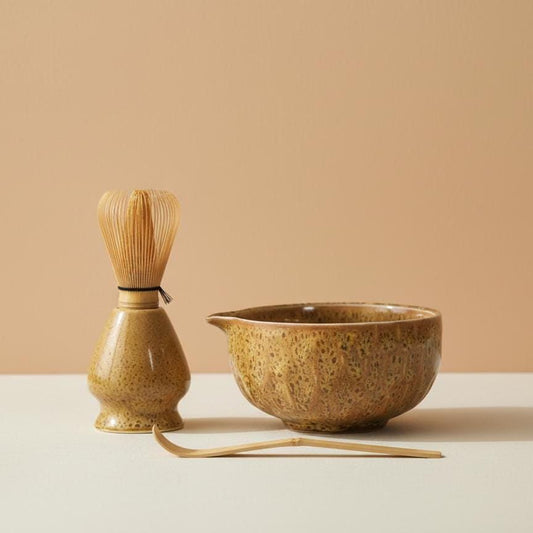 Ceramic tea set with whisk and bowl on a beige background